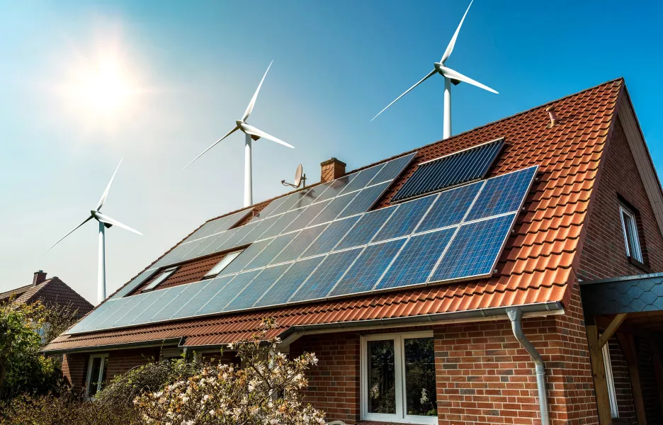 Maison avec éolienne et panneaux solaires et géothermie pour symboliser le mix d'énergies renouvelables idéal. 